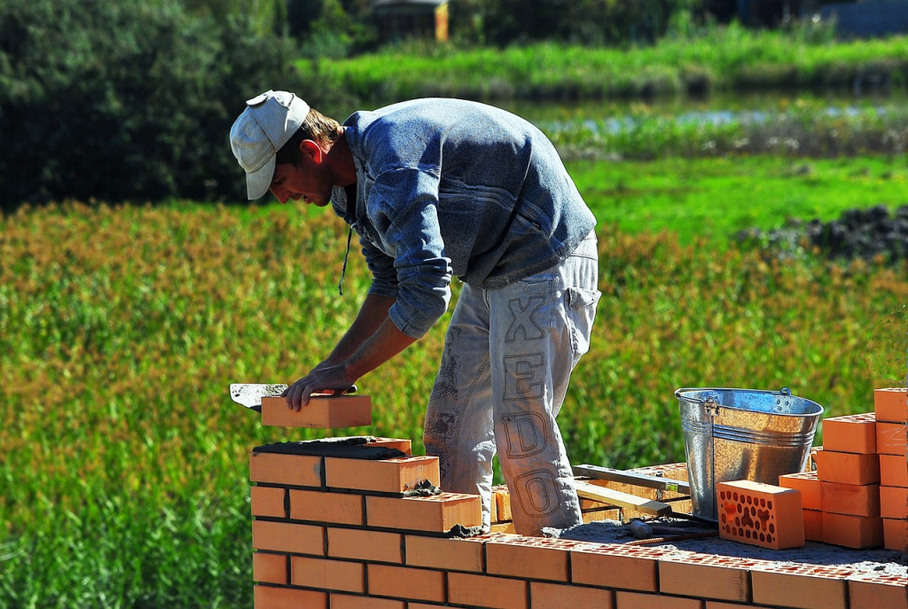 person constructing a brick wall