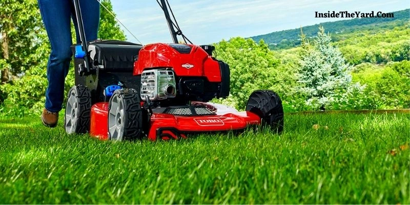 a person mowing lawn with red colored mower